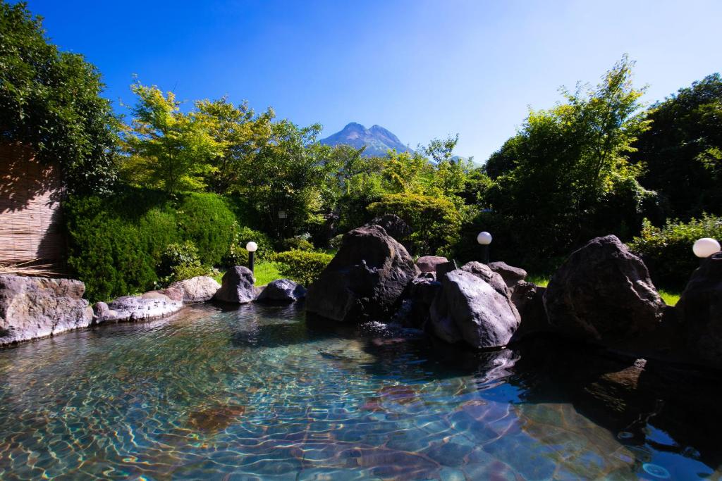 un bassin d'eau avec des rochers et des arbres dans l'établissement Yufuin Sansuikan, à Yufu