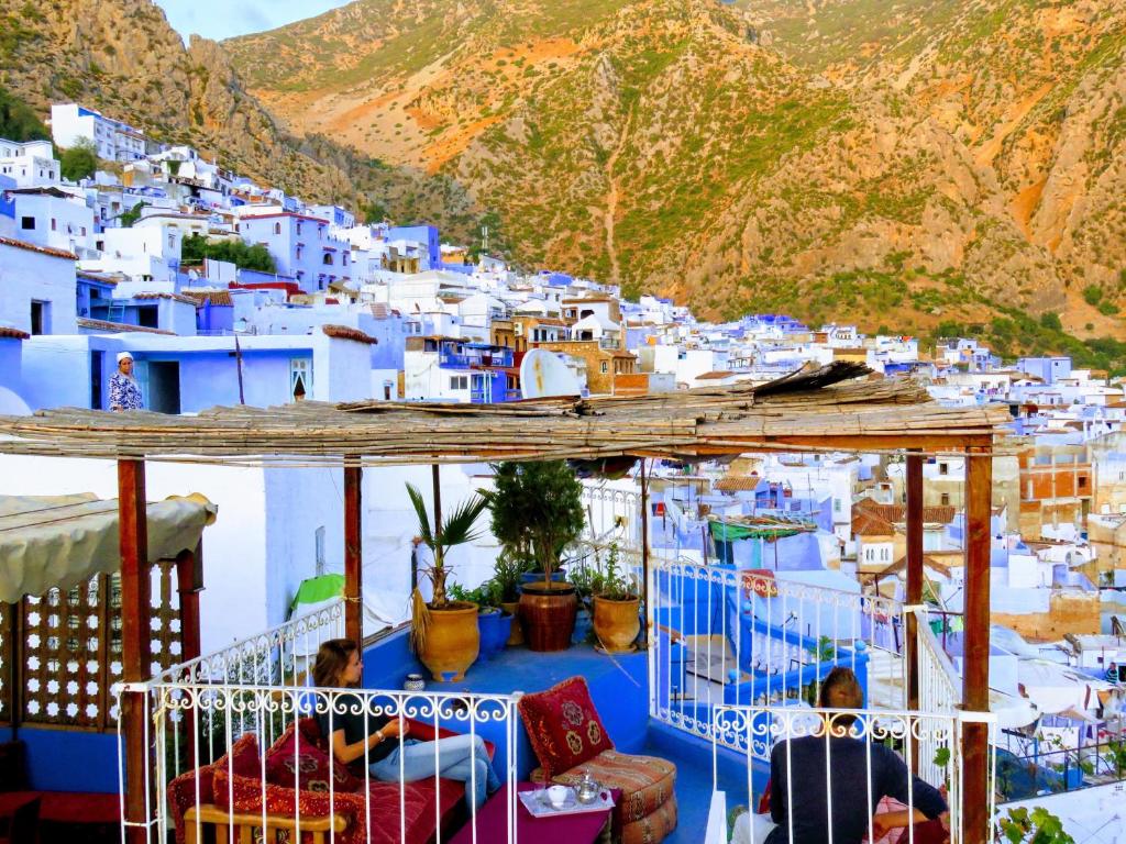 un groupe de personnes assises sur un balcon en face d'un village dans l'établissement Dar Sababa, à Chefchaouen