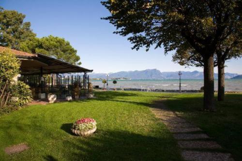 une cour avec un pot de fleurs sur l'herbe dans l'établissement Hotel Lugana Parco Al Lago, à Sirmione