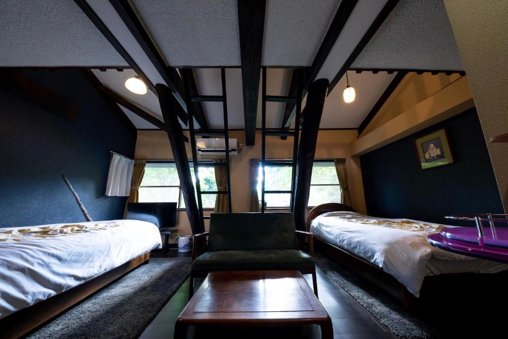 - une chambre avec deux lits, une chaise et une table dans l'établissement Taisho Yufu no Hana, à Yufu
