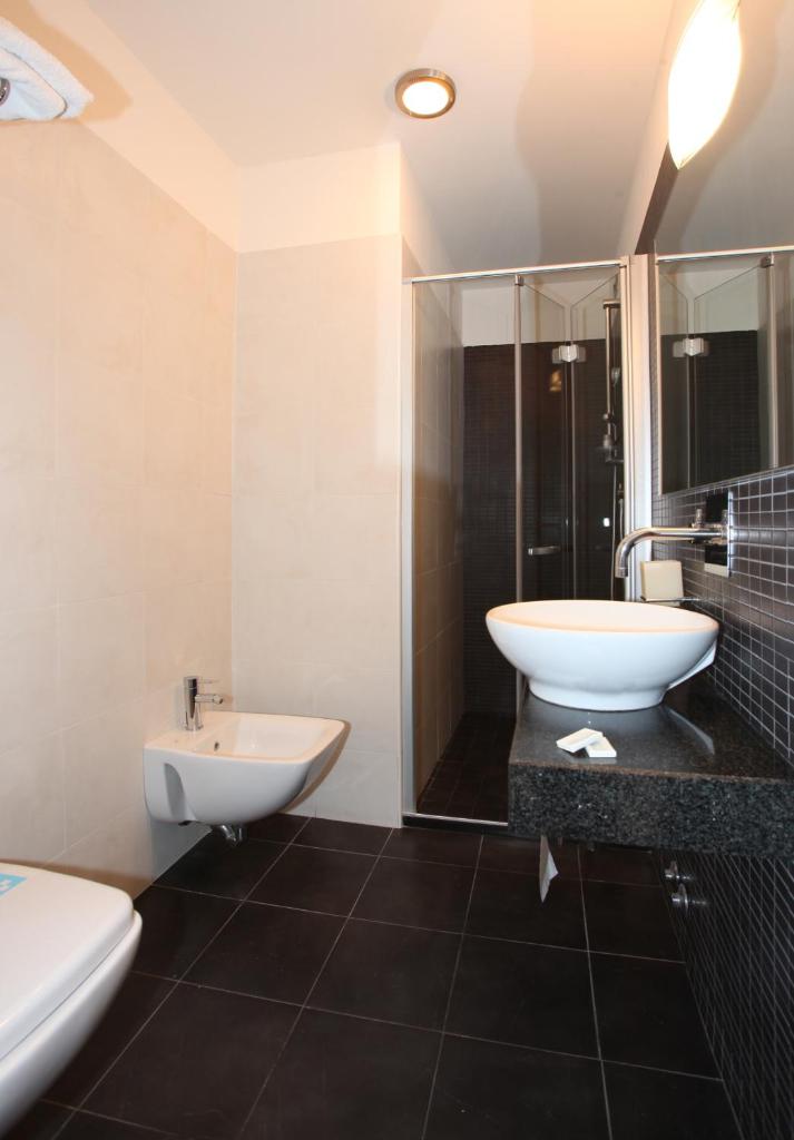 une salle de bain avec un lavabo, des toilettes et une douche dans l'établissement Hotel Santiago, à Lido di Jesolo