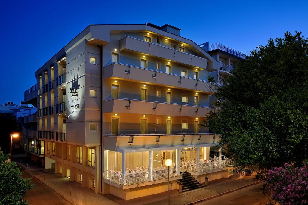 un grand bâtiment avec des lumières allumées la nuit dans l'établissement Hotel Principe, à Cattolica