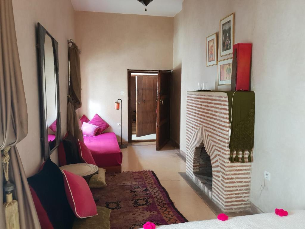 - un salon avec une cheminée et une chaise rose dans l'établissement Dar Warda, à Marrakech