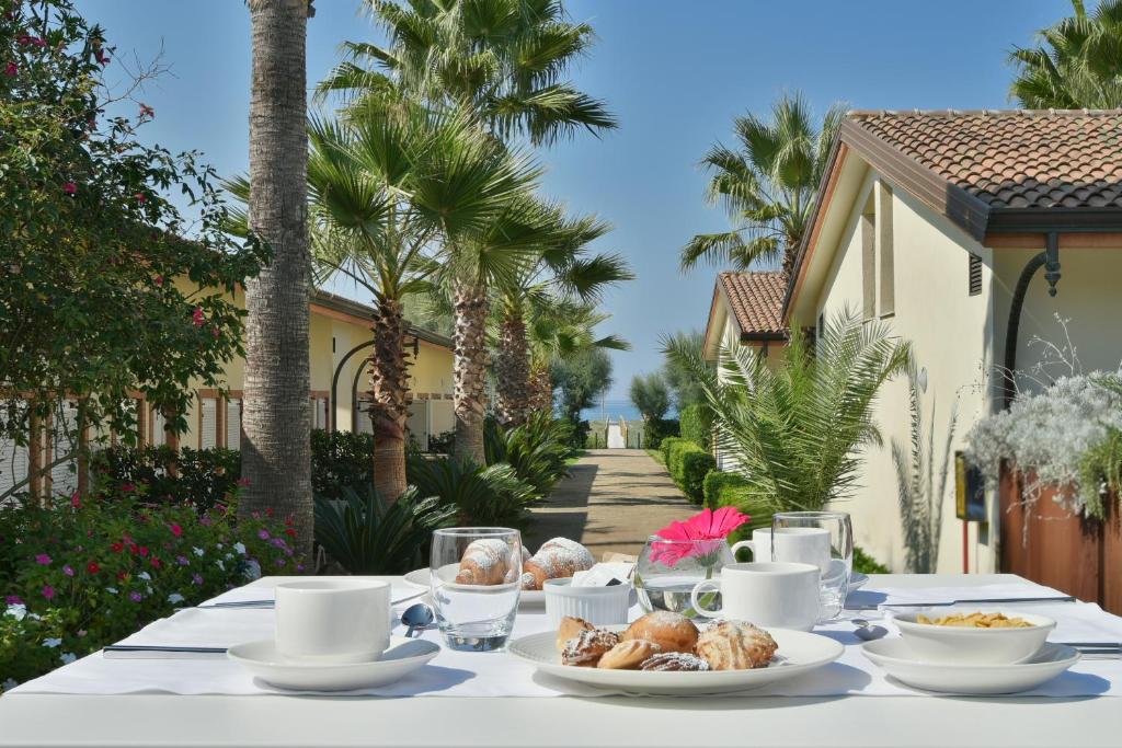 une table avec de la nourriture devant une maison dans l'établissement Paestum Inn Beach Resort, à Paestum