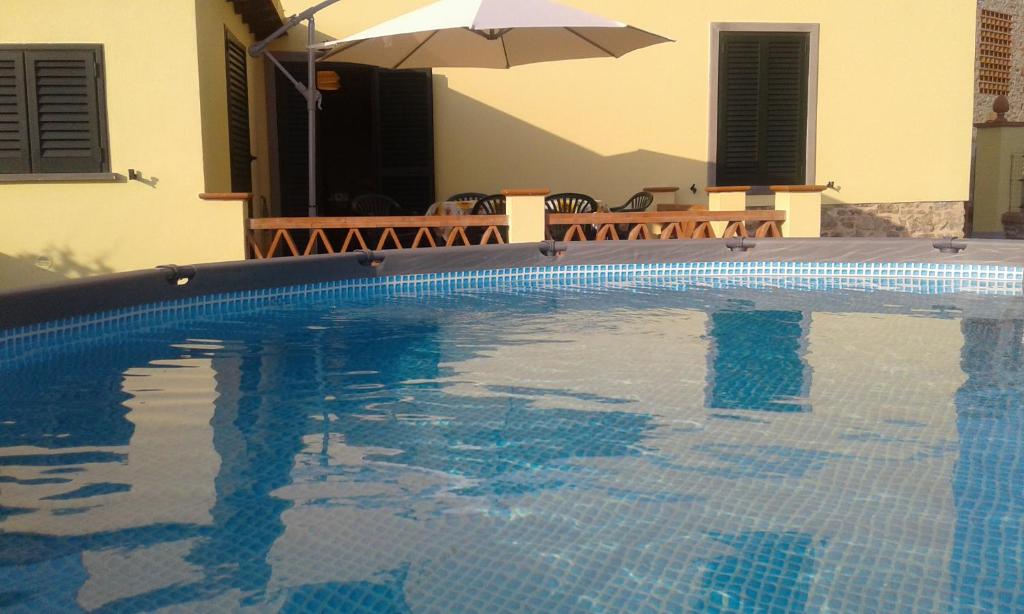 - une piscine avec un parasol à côté d'une maison dans l'établissement CA' MENEGHETTI, à Massaciuccoli