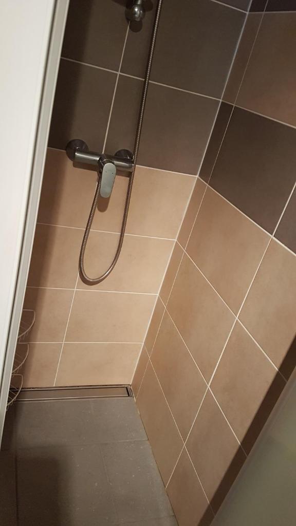 - une douche avec un pommeau sur le sol carrelé dans l'établissement Studio-cabine au pied des pistes à Super Besse, à Super-Besse