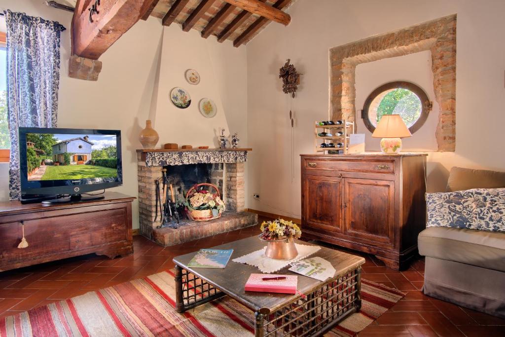 un salon avec une télévision et une cheminée dans l'établissement villa la chiesetta - private pool - Borgo Canapegna, à Fabriano