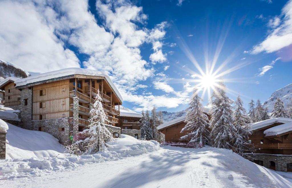 un lodge dans la neige avec le soleil dans le ciel dans l'établissement Les Chalets Du Jardin Alpin, à Val dʼIsère