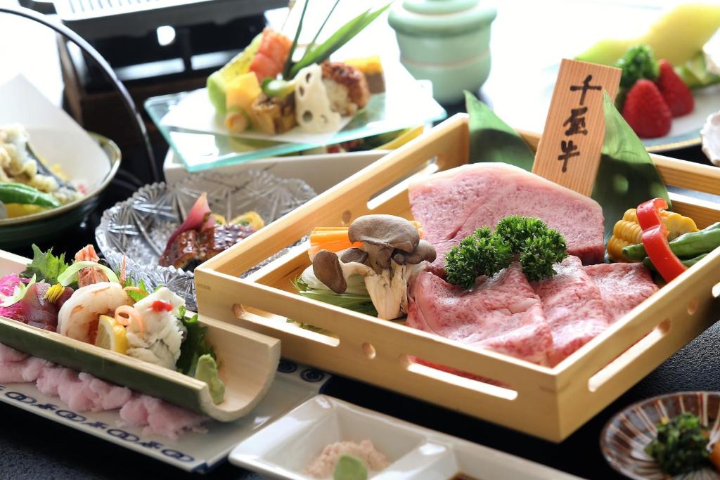 un plateau de nourriture avec de la viande et des légumes sur une table dans l'établissement Okutsu Onsen Komeya Club, à Kagamino