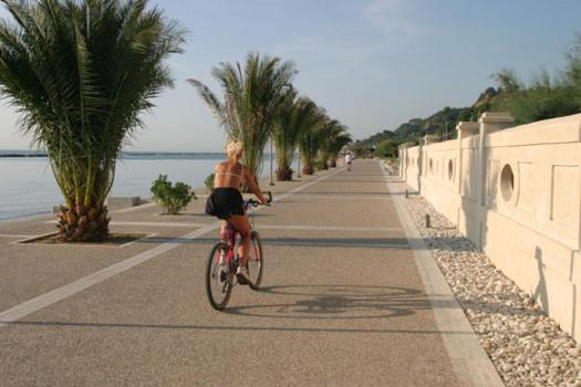 Une femme à vélo sur une route à côté de l'océan dans l'établissement Residence Stella Marina, à Cupra Marittima