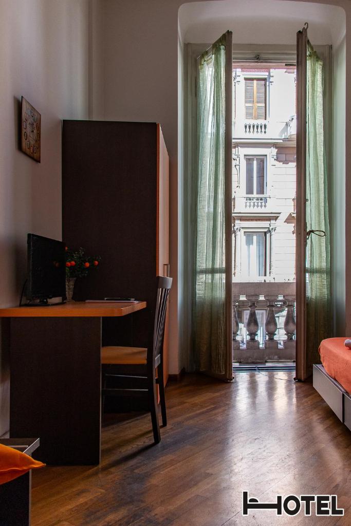 Cette chambre comprend un bureau, une table et une fenêtre. dans l'établissement Hotel Youri Il Magnifico, à Gênes