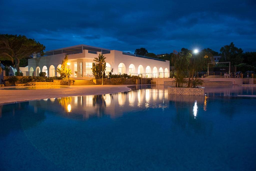 - un bâtiment avec une grande piscine d'eau la nuit dans l'établissement Mon Rêve Resort, à Tarente