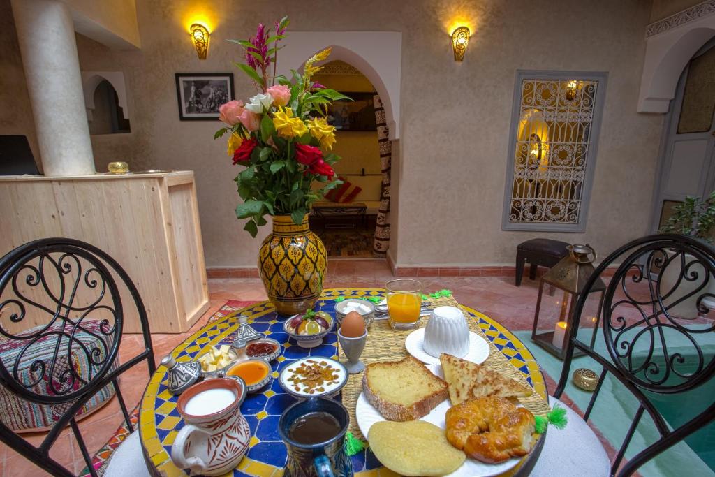 une table avec une assiette de nourriture et un vase de fleurs dans l'établissement Dar Picolina, à Marrakech