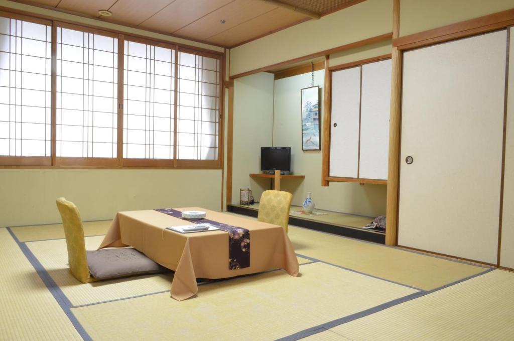 une pièce avec une table, des chaises et une télévision dans l'établissement Nissho Besso, à Kyoto