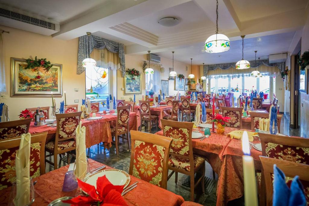 un restaurant avec des tables et des chaises avec des nappes rouges dans l'établissement Albergo Ristorante Fabrizio, à Caorle