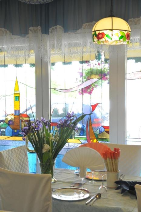 une table à manger avec des fleurs et un lustre dans l'établissement Albergo Ristorante Fabrizio, à Caorle