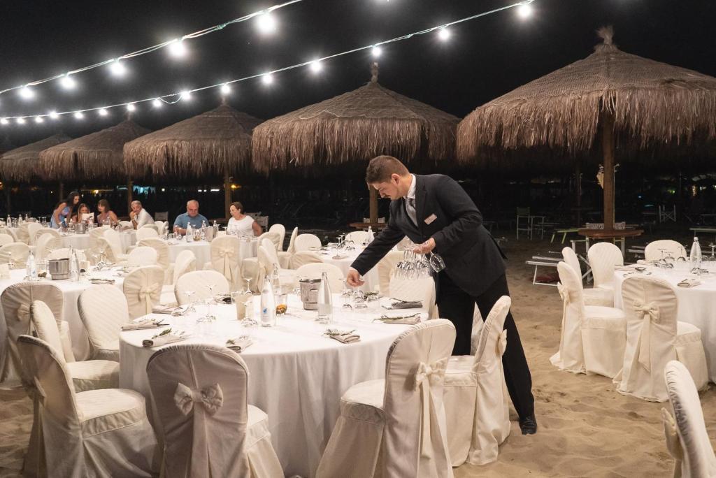un homme debout devant une table avec des tables blanches dans l'établissement Grand Hotel Don Juan, à Giulianova 54 autres photos
