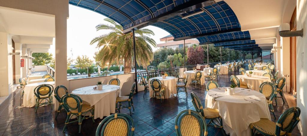 un restaurant avec des tables et des chaises blanches sur un balcon dans l'établissement Grand Hotel Don Juan, à Giulianova