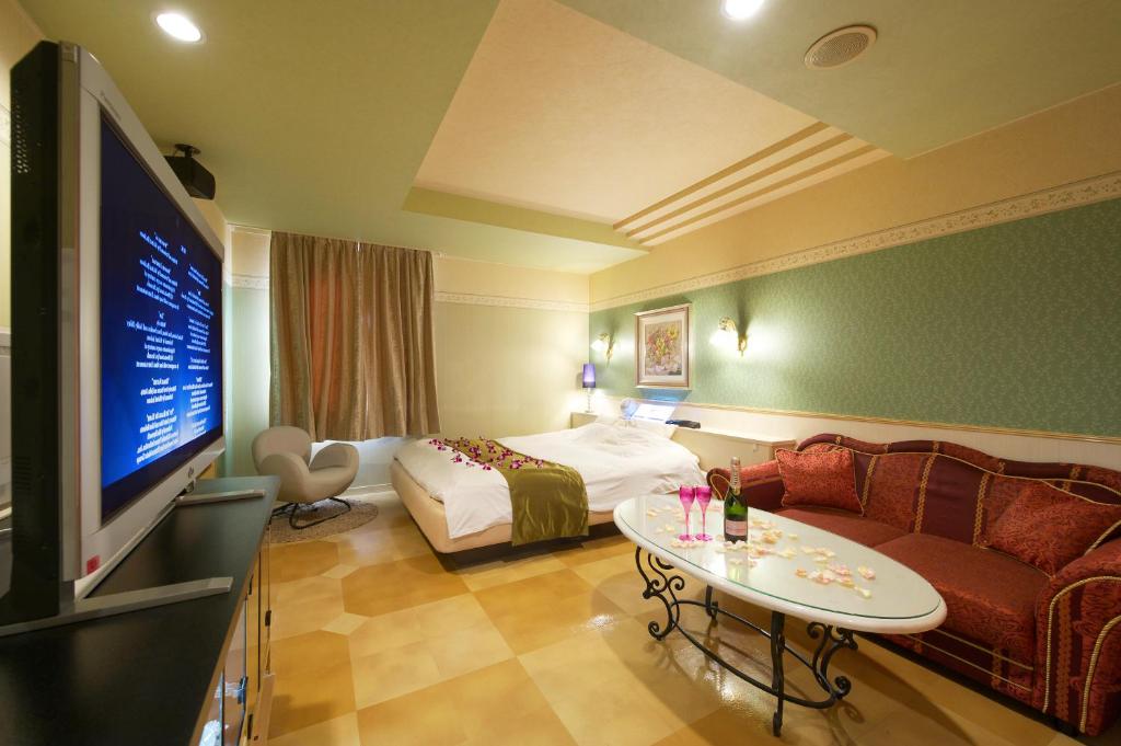une chambre d'hôtel avec un lit, un canapé et une télévision dans l'établissement Hotel Park Inn (Adult Only), à Matsuyama