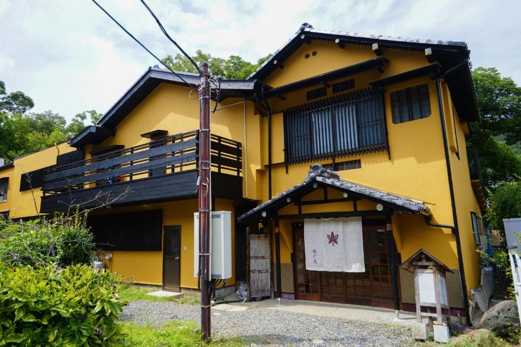 une maison jaune avec un poteau en face de celle-ci dans l'établissement Onsen Yado Mizuguchi, à Izu