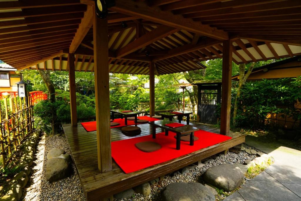 un gazebo en bois avec des tables de pique-nique sur un tapis rouge dans l'établissement Onsen Yado Mizuguchi, à Izu