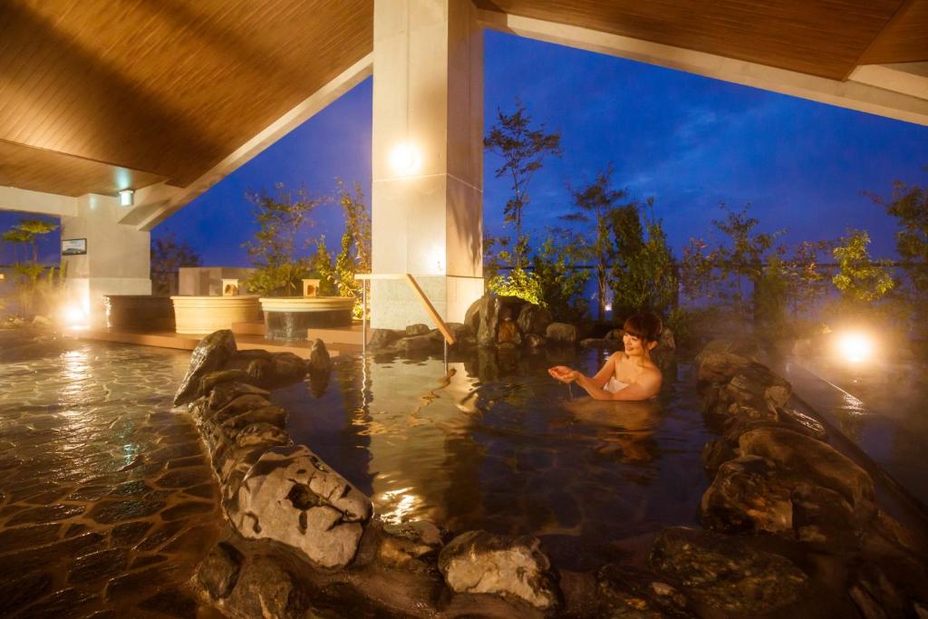 une femme assise dans une piscine d'un complexe la nuit dans l'établissement Hotel Mori no Kaze Nasu, à Nasu