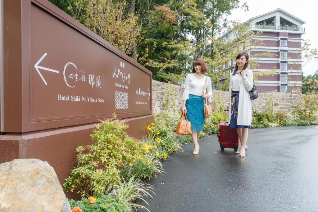 deux femmes marchant dans une rue avec leurs bagages dans l'établissement Hotel Mori no Kaze Nasu, à Nasu