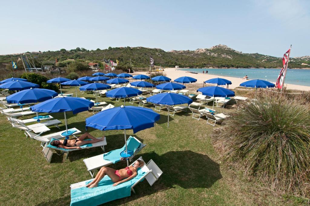 un groupe de personnes se posant sur une plage avec des parasols bleus dans l'établissement Hotel Palau, à Palau