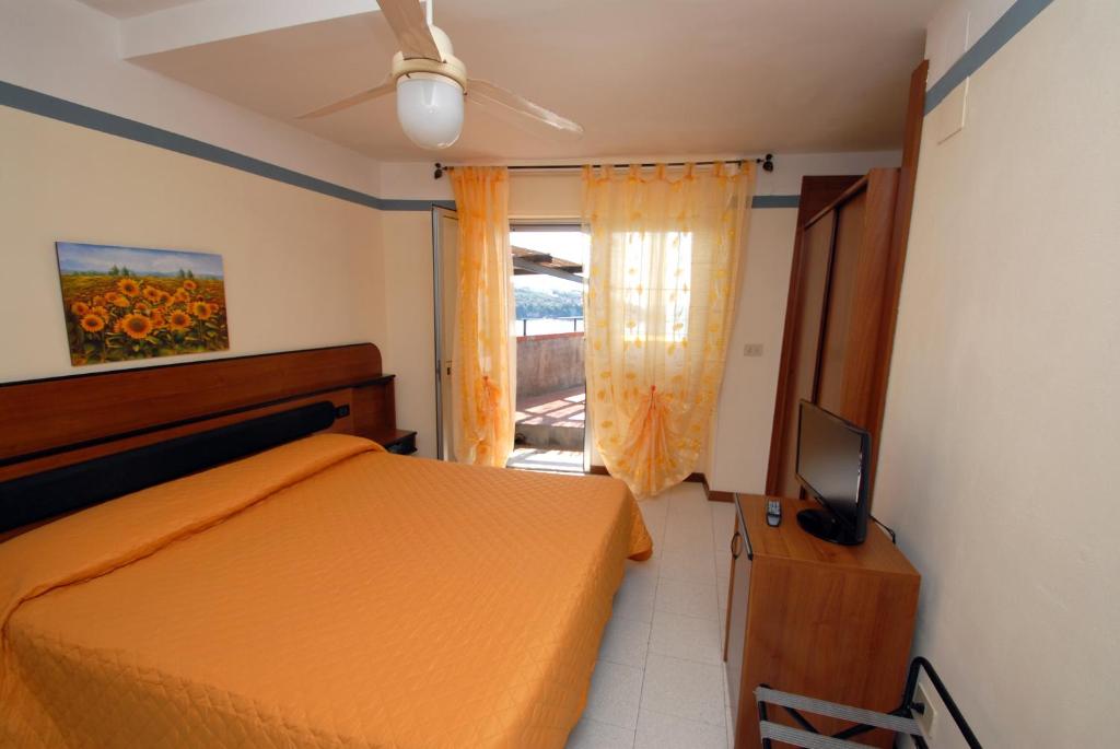 une chambre avec un lit orange et une télévision dans l'établissement Hotel Baia Del Sorriso, à Castiglioncello