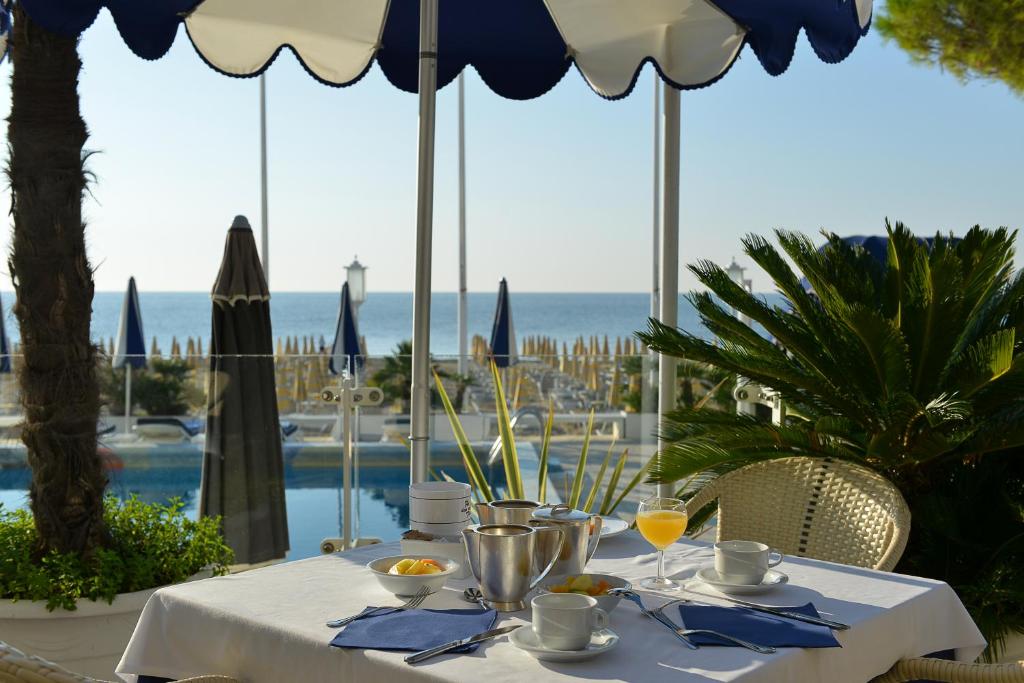 une table avec de la nourriture et des boissons dessus avec vue sur l'océan dans l'établissement Hotel Anthony, à Lido di Jesolo