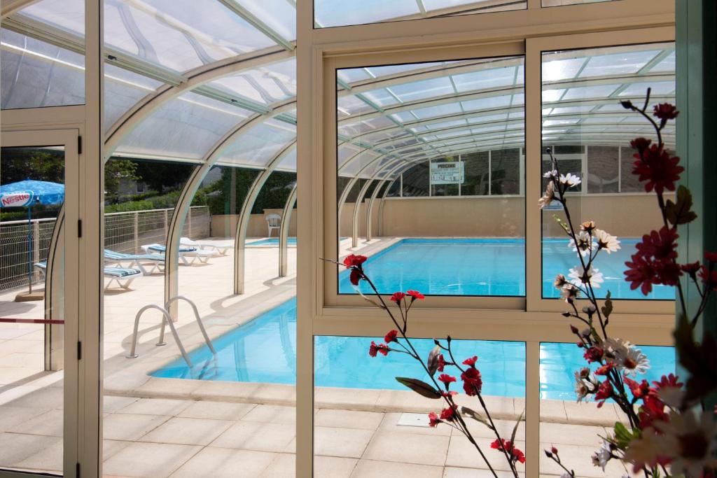 - une piscine à l'intérieur d'un bâtiment avec un toit en verre dans l'établissement Parc du Charouzech, à Salles-Curan