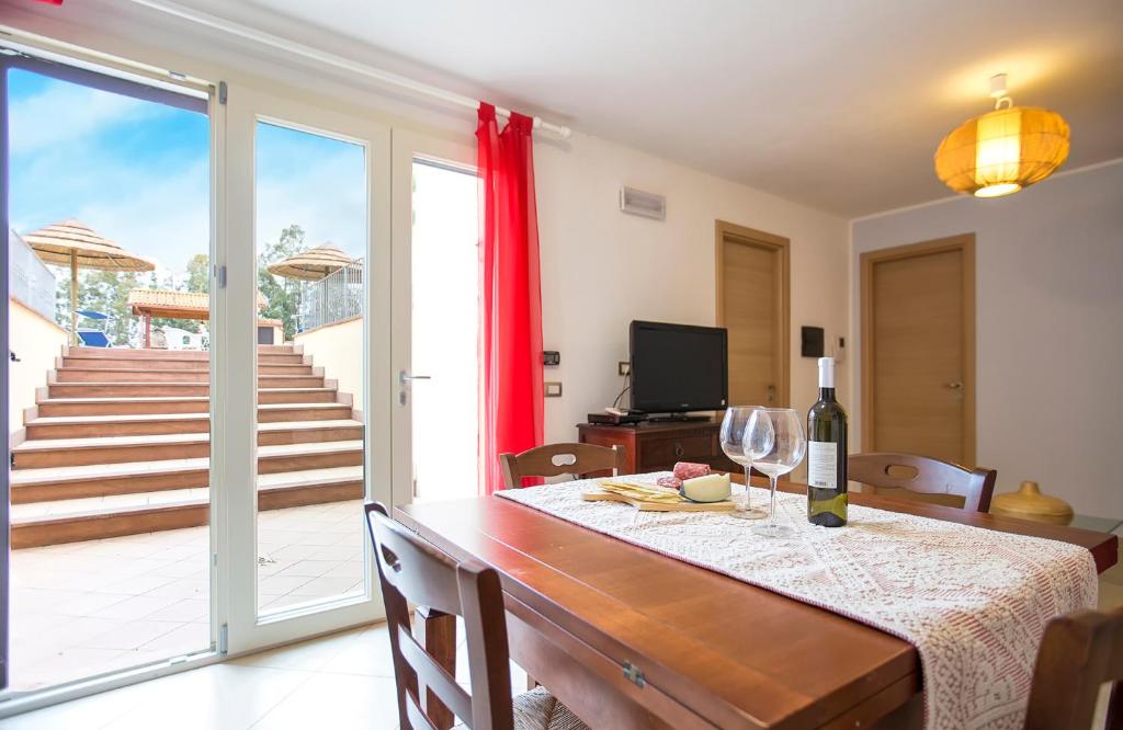 une salle à manger avec une table et un verre de vin dans l'établissement Alghero Villa Morena with exclusive swimming pool and large garden, à Alghero