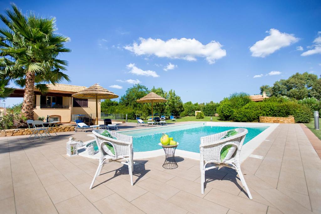 un patio avec des chaises et une piscine dans l'établissement Alghero Villa Morena with exclusive swimming pool and large garden, à Alghero