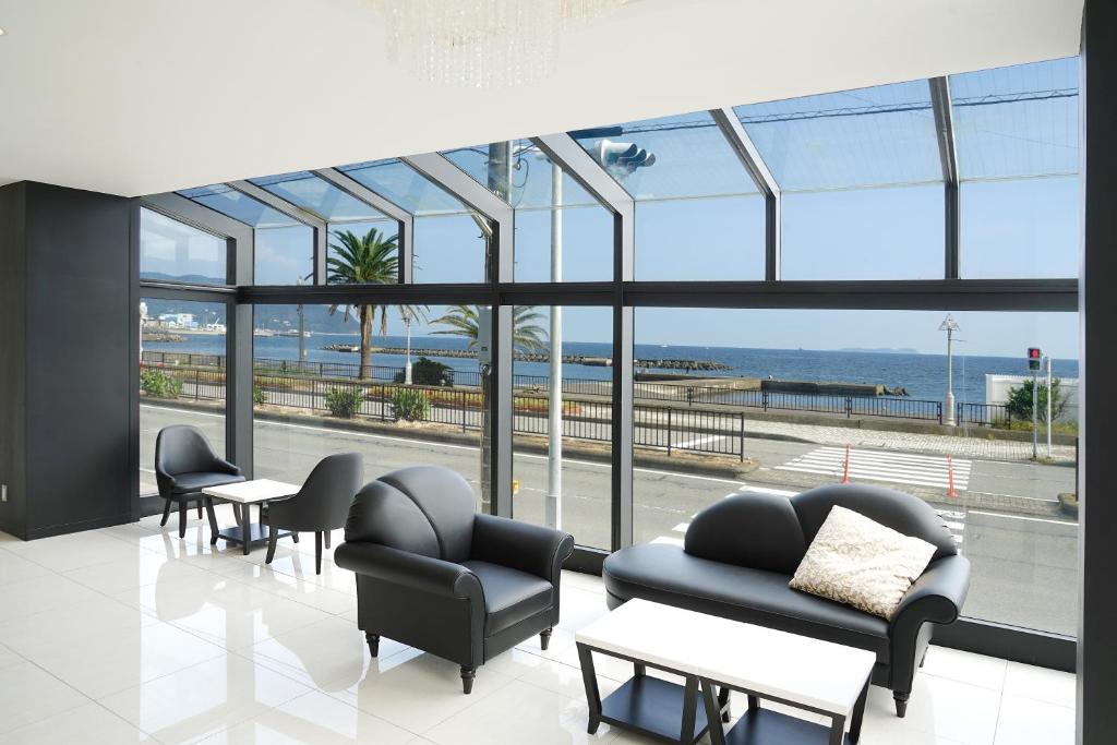 - une salle d'attente avec des chaises, des tables et de grandes fenêtres dans l'établissement SEVEN SEAS HOTEL ITO (セブンシーズホテル）, à Itō
