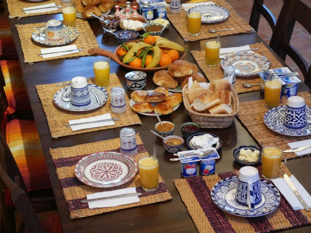 une longue table remplie de nourriture et de jus d'orange dans l'établissement Riad Akour, à Merzouga