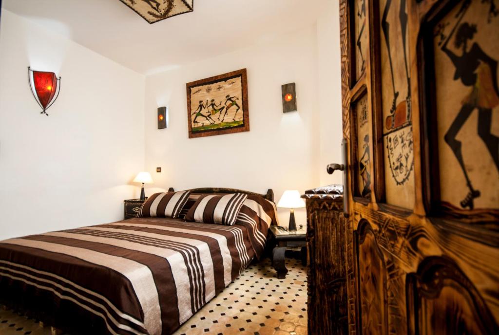 - une chambre avec un lit et une porte en bois dans l'établissement Riad Bab Essaouira, à Essaouira