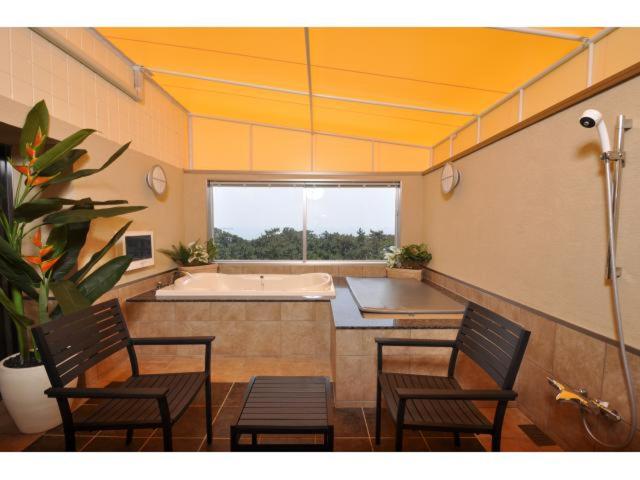 Cette grande chambre dispose d'une baignoire, de deux chaises et d'une table. dans l'établissement Hotel ShaSha Resort Suma, à Kobe