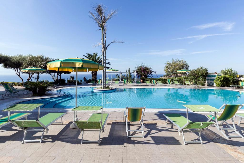 une piscine avec chaises et parasols au bord de l'océan dans l'établissement Hotel Residence Sciaron, à Capo Vaticano