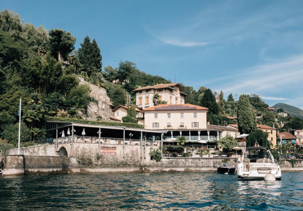 un bateau dans l'eau devant une maison dans l'établissement Relais Villa Porta, à Luino