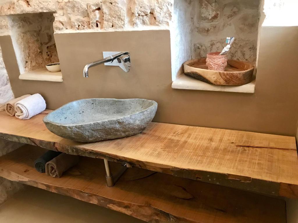 La salle de bains est pourvue d'un lavabo en pierre sur une table en bois. dans l'établissement Trulli Storie di Puglia - Private Pool, à Polignano a Mare