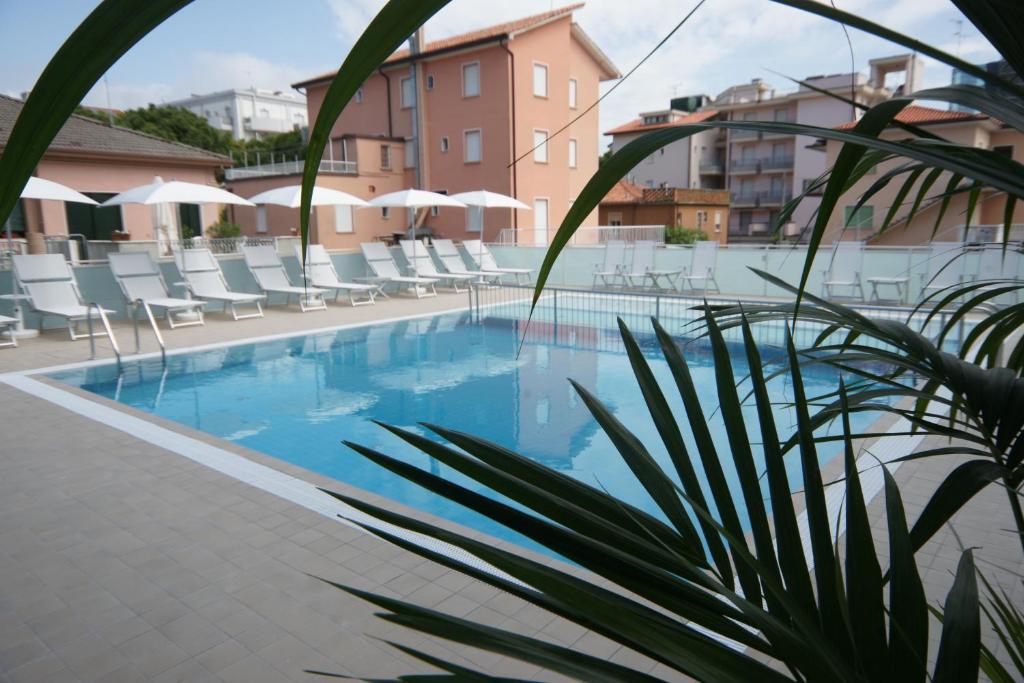 une piscine avec des chaises et un hôtel dans l'établissement Hotel Albatros 3 Stelle Superior, à Lido di Jesolo