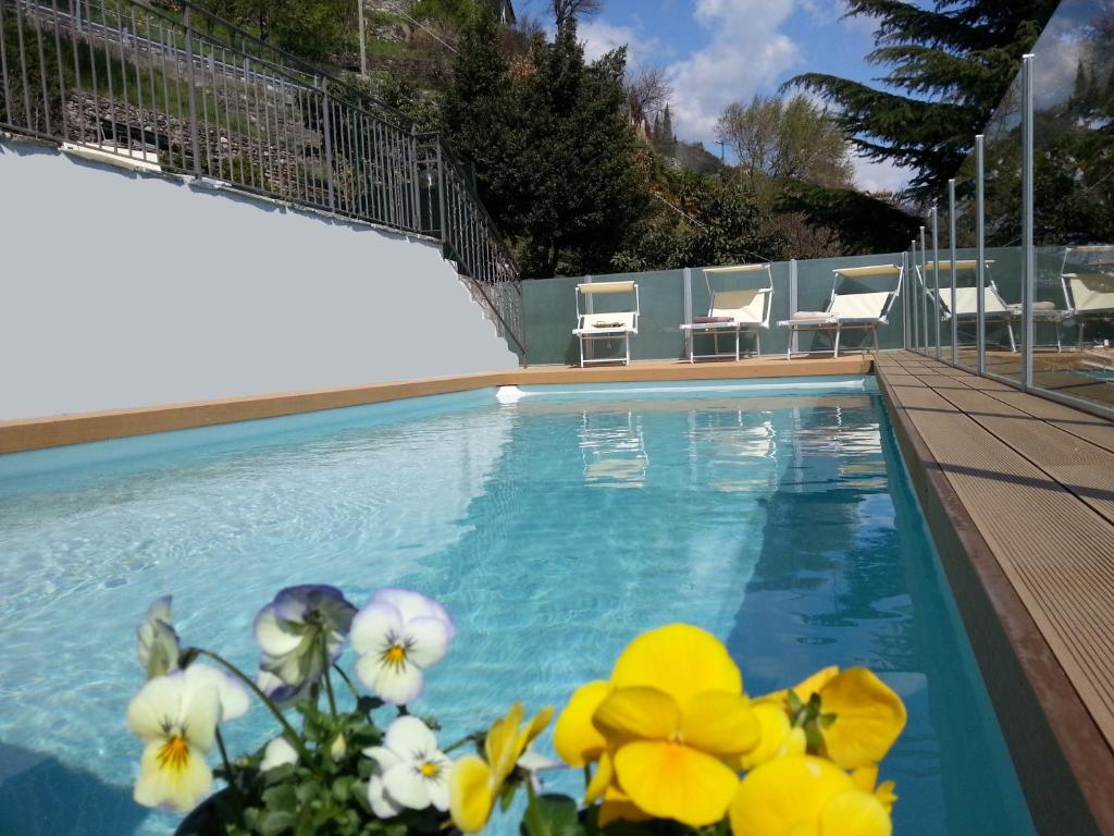 - une piscine d'eau bleue et de fleurs jaunes à côté dans l'établissement Villa Perla del Lago, à Vercana