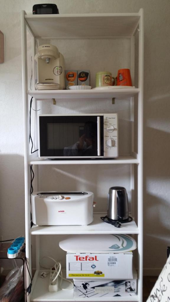 une étagère blanche avec un four micro-ondes. dans l'établissement Studio-cabine au pied des pistes à Super Besse, à Super-Besse