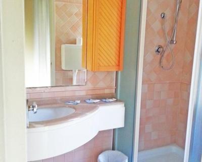 une salle de bain avec un lavabo, un miroir et une douche dans l'établissement Hotel Glenn, à Rimini