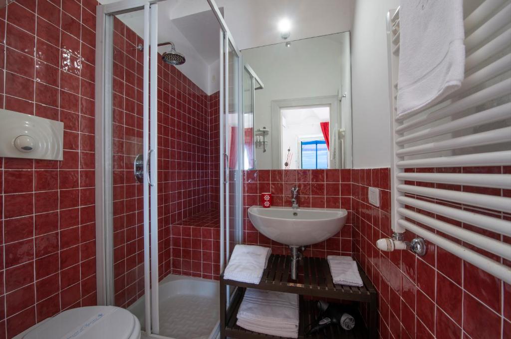La salle de bains est pourvue de carrelage rouge, d'un lavabo et d'une douche. dans l'établissement Villa Knight, à Amalfi