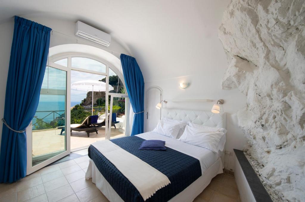 Cette chambre comprend un lit avec des rideaux bleus et un balcon. dans l'établissement Villa Knight, à Amalfi