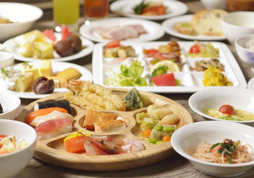 une table avec de nombreuses assiettes de nourriture dessus dans l'établissement Jozankei Manseikaku Hotel Milione, à Jozankei