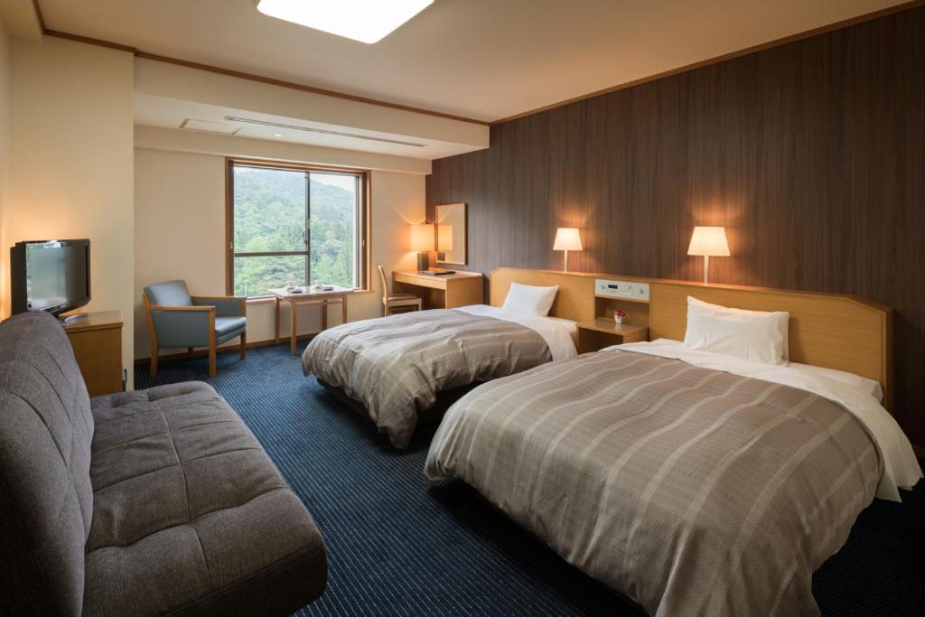 une chambre d'hôtel avec deux lits et un canapé dans l'établissement Hotel Senshukaku, à Hanamaki