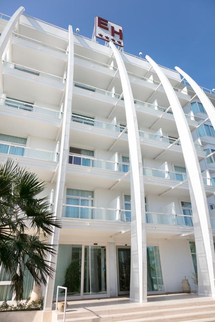 un immeuble d'appartements blanc avec des colonnes blanches et un palmier dans l'établissement Hotel Excelsior, à Vasto