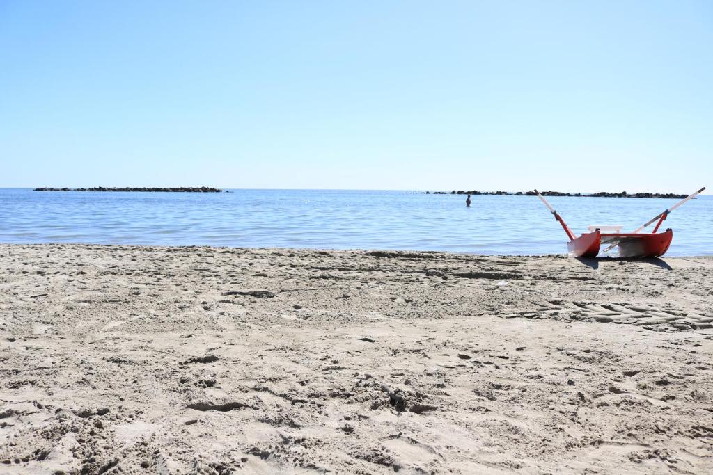 - un bateau rouge assis sur une plage au bord de l'eau dans l'établissement Residence Eden, à Comacchio
